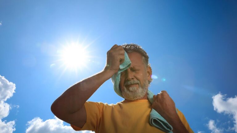 Persona bebiendo agua a la sombra durante un día de calor intenso.