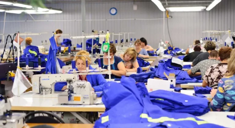 Fábrica textil con rollos de tela y máquinas de coser en un entorno industrial.